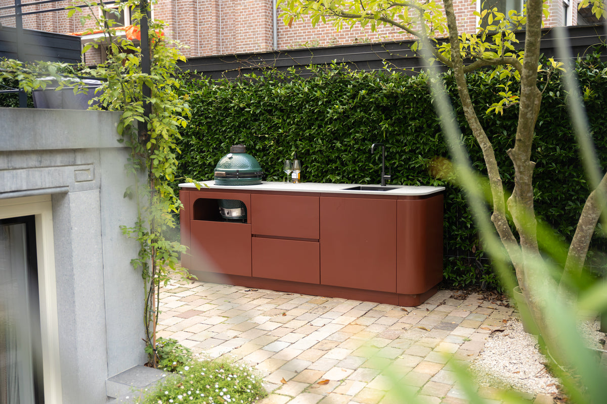 Een buitenkeuken kleur die opvalt tussen het groen